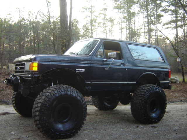 Lifted 1989 Ford Bronco with large tires parked on a dirt road