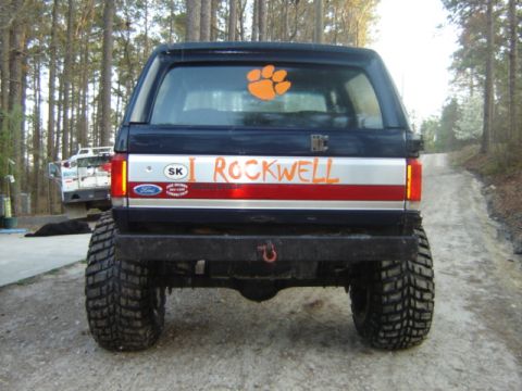 1989 Ford Bronco - Rear view of a modified black Ford Bronco with large tires and custom paint.