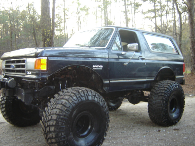 Dark blue lifted Ford Bronco with large off-road tires, parked outdoors