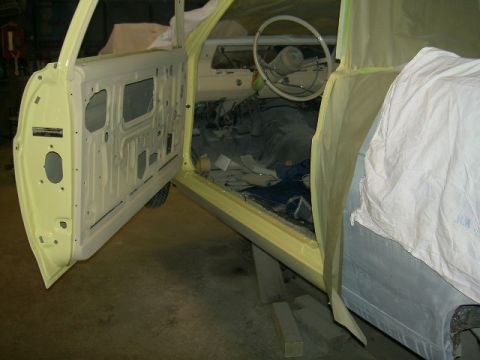 1967 Ford Ranchero - The interior of a yellow 1967 Ford Ranchero is visible with the driver's door open, showing the dashboard and seats during a restoration pr…