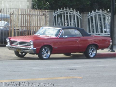 1968 Ford Mustang - A red 1965 Pontiac Tempest convertible is seen from the side, parked on a street.