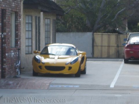 1968 Ford Mustang - A yellow Lotus Elise is parked in a lot next to a red sports car.