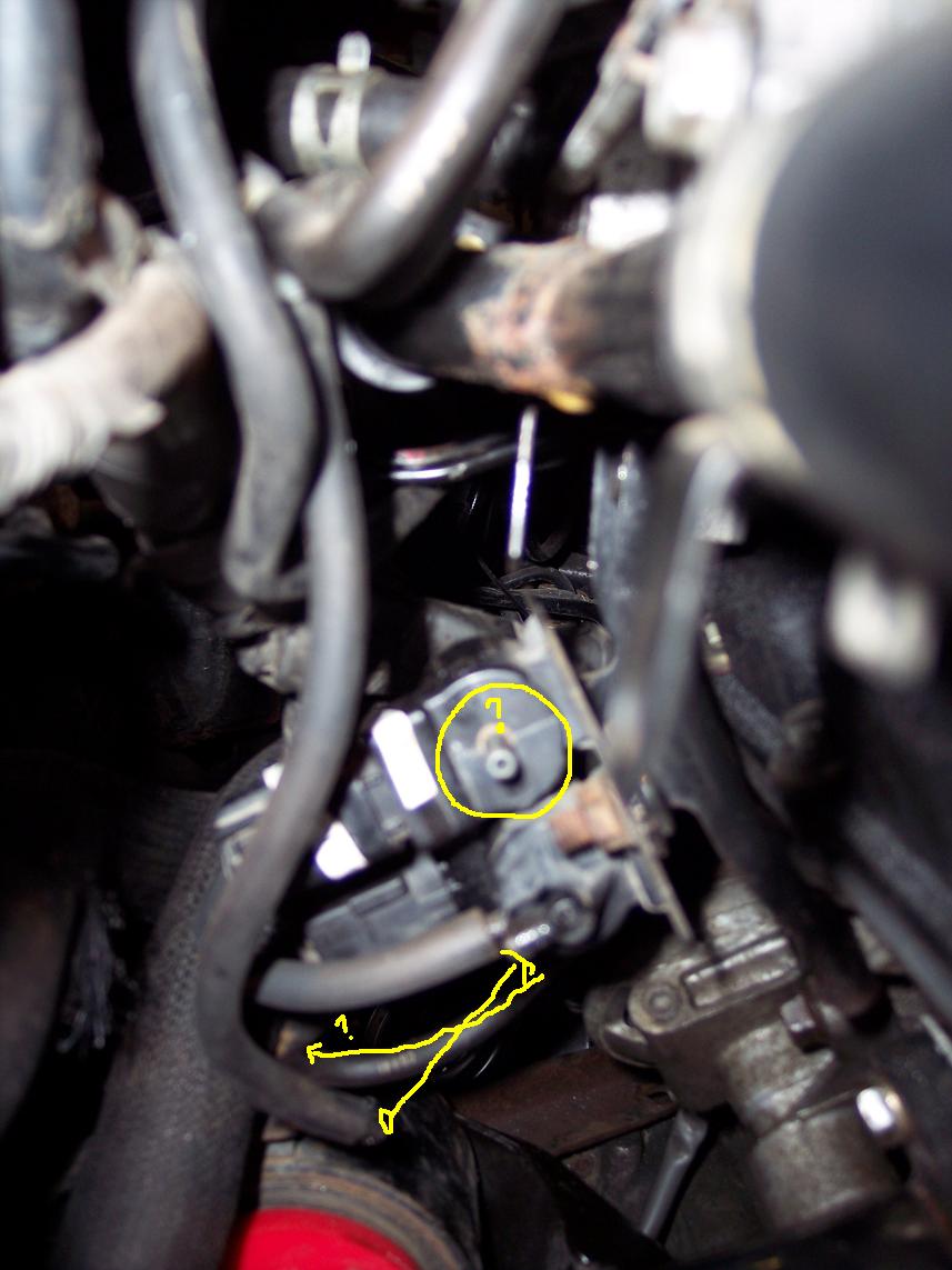 Close-up of engine bay hoses and a sensor with yellow markings