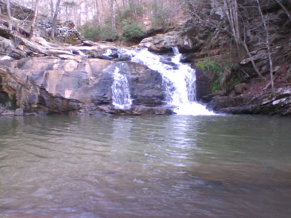 Waterfall flowing over rocks into a calm pool in a bare winter forest