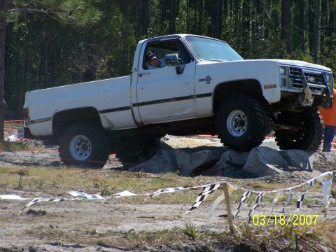 1989 Ford Bronco - A white pickup truck navigates an off-road obstacle course.