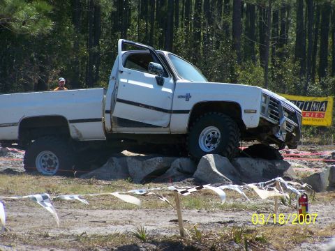 1989 Ford Bronco - This white pickup truck, likely a 1989 model based on its body style, is shown tackling an obstacle course on rocks.
