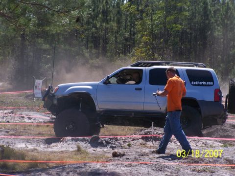 1989 Ford Bronco - Off-road event with a silver SUV on a dirt track. A person is observing the vehicle's progress.