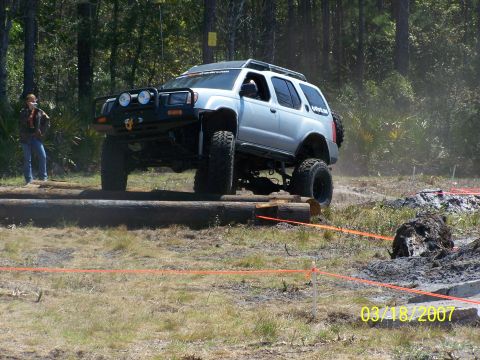 1989 Ford Bronco - An off-road SUV navigates a challenging course marked with orange ropes.