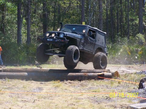 1989 Ford Bronco - A modified Jeep Wrangler jumps over a series of logs during an off-road event.