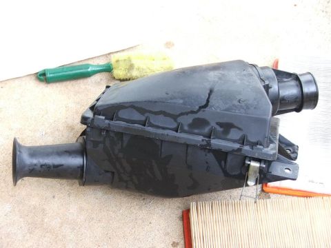 1991 Ford LTD Crown Victoria - A black plastic air cleaner housing is shown with a cleaning brush and a new air filter.