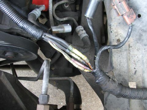 1991 Ford LTD Crown Victoria - Close-up view of a damaged engine wiring harness with exposed wires and electrical tape.