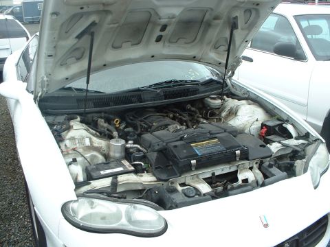 2000 Ford Crown Victoria - Engine bay of a white car, hood is open showing engine components and battery.