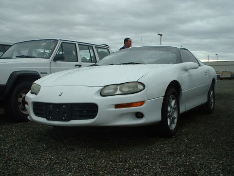 2000 Ford Crown Victoria - White 1998 Chevrolet Camaro and a white Jeep Cherokee are parked outdoors on a cloudy day.