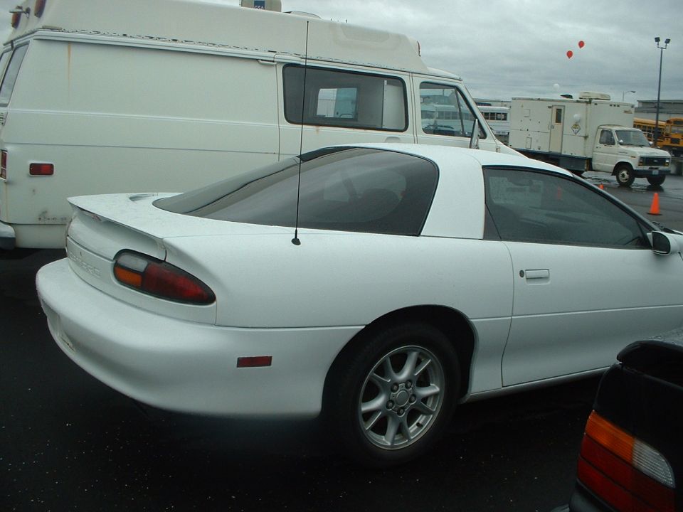 White coupe parked next to a white van. The coupe has a spoiler and a black interior