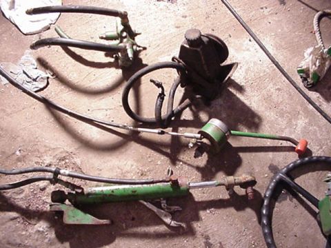 1992 Ford Bronco - Automotive parts, including a power steering pump and hydraulic cylinder, are laid out on a concrete floor.