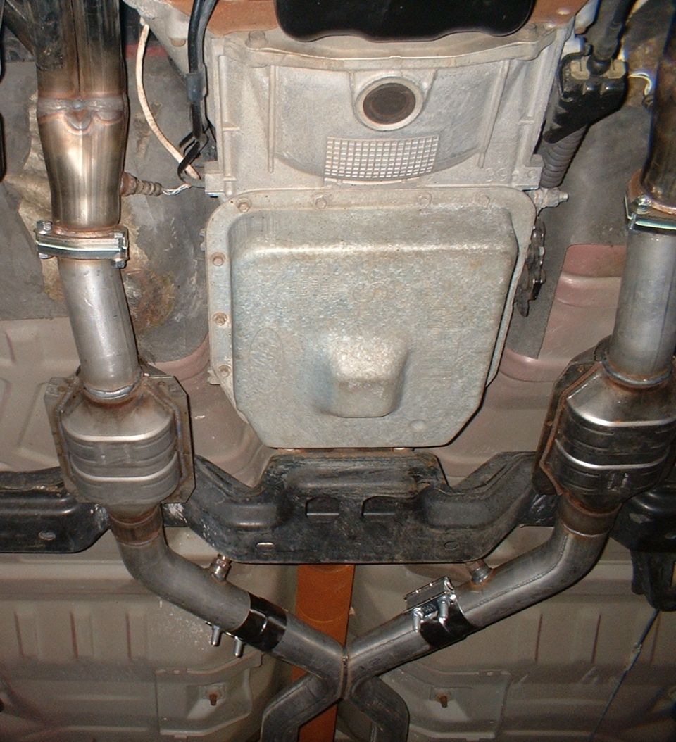 Underside view of transmission pan with dual exhaust pipes and catalytic converters
