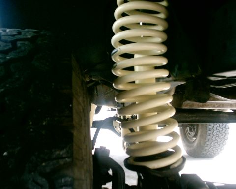 1979 Ford Bronco - This image shows a close-up view of a vehicle's suspension system, focusing on a coil spring and tire.