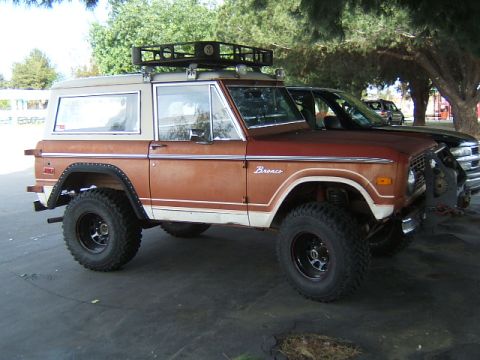 1988 Ford Bronco - This vintage Ford Bronco features a two-tone paint scheme and a roof rack, parked outdoors.