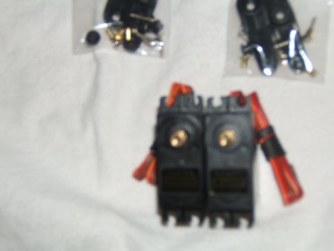 1988 Ford Bronco - Close-up of two RC servo motors and assorted hardware laid out on a white surface.