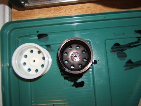 1988 Ford Bronco - A white plastic RC car wheel and a metal hub are shown on a green tray.