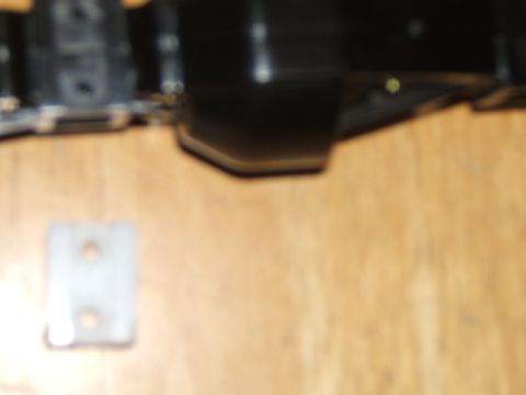 1988 Ford Bronco - A close-up view of a black plastic component and a metal bracket on a wooden surface.