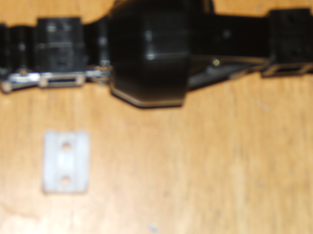RC car axle assembly and a small white plastic mount on a wooden surface