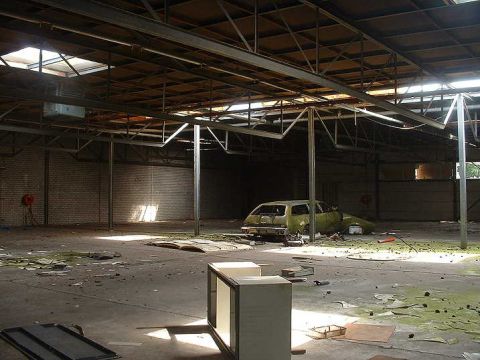 1979 Ford Bronco - Derelict warehouse interior with an abandoned car and debris scattered across the floor.