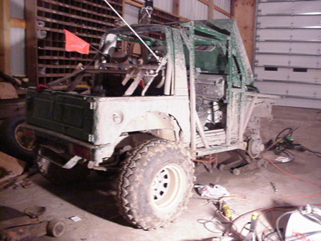 Off-road vehicle with roll cage and large tires, in a workshop