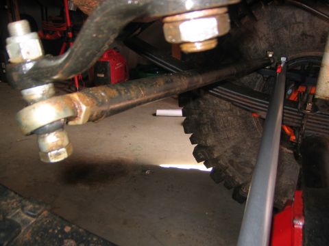 1979 Ford Bronco - This photo shows the steering linkage of a vehicle, including the tie rod and drag link, with a tire and leaf springs in the background.