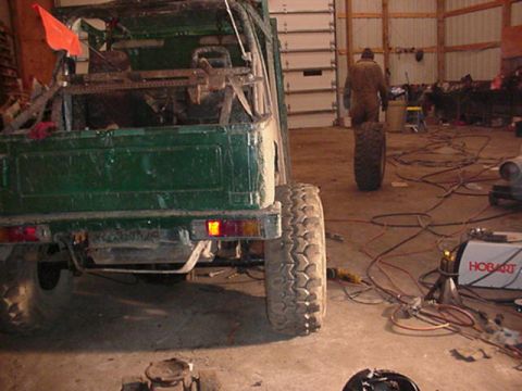 1992 Ford Bronco - A green off-road vehicle is parked in a garage with a person walking in the background.
