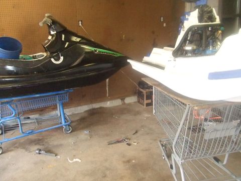 1995 Ford Mustang - Two watercraft, a jet ski and a boat hull, are stored in a garage.
