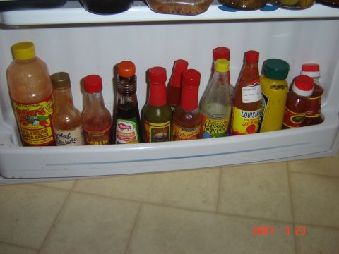 1993 Ford Bronco - A collection of hot sauce bottles is stored on a shelf, likely in a refrigerator.