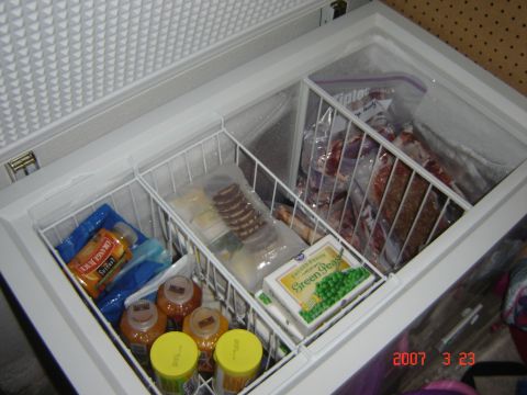 1993 Ford Bronco - A chest freezer is packed with various frozen food items, organized in wire baskets.