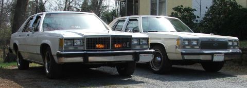 1991 Ford LTD Crown Victoria - Two Ford Crown Victorias are parked in a driveway, showing their front ends.