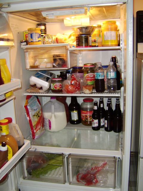 1989 Ford Bronco - A full refrigerator with shelves stocked with condiments, jars, bottles, and produce in drawers.