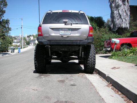 1999 Jeep Grand Cherokee - This lifted 1999 Jeep Grand Cherokee features oversized tires and a modified suspension, parked on a residential street.