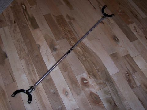 1995 Ford Probe - A racing strut tower brace is shown on a wooden floor, with text visible on the brace itself.