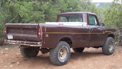 1990 Ford Bronco - This brown pickup truck features prominent International badging on the tailgate and is equipped with off-road tires.
