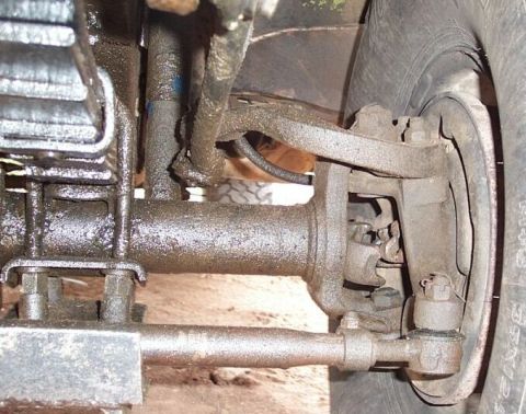 1990 Ford Bronco - Undercarriage view of vehicle suspension and steering parts, covered in grease.