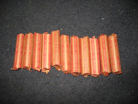 1997 Ford Crown Victoria - Ten rolls of pennies, each marked as 50 cents, are laid out on a dark, textured surface.