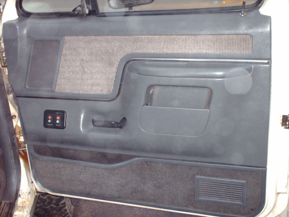 Gray interior door panel with fabric insert, pull handle, and aftermarket switch panel