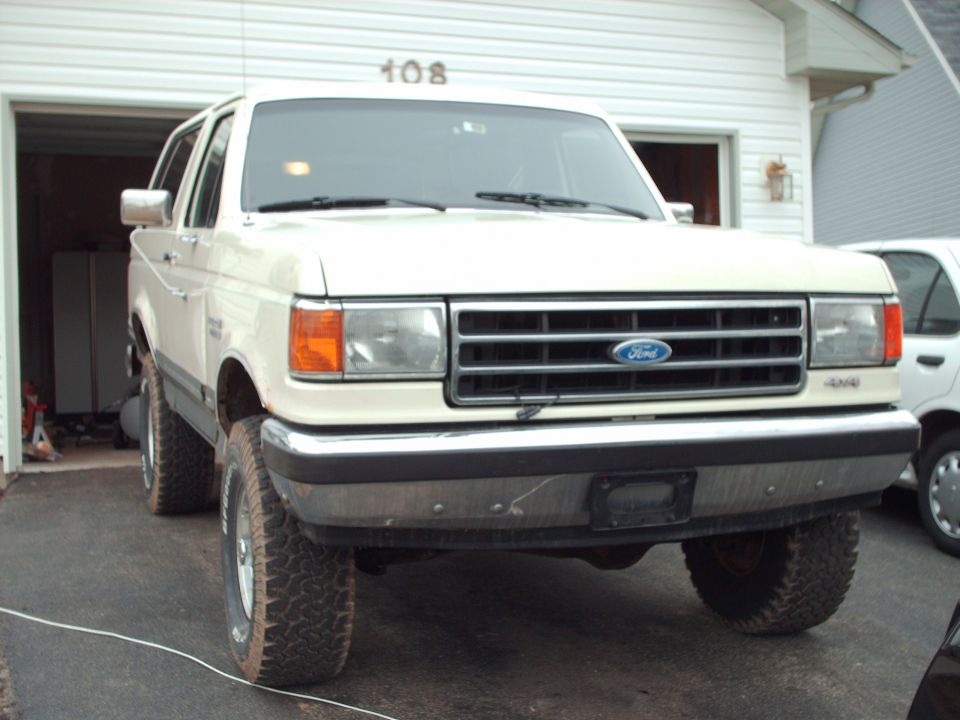 1990 Ford Bronco parked in front of a garage