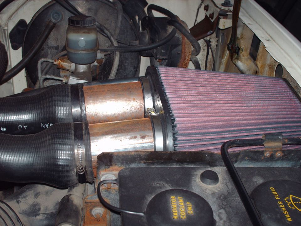 Engine bay showing aftermarket air filter, hoses, and brake fluid reservoir