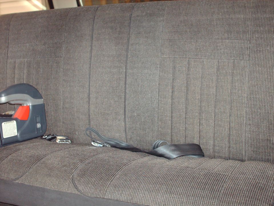 Back seat of a vehicle with a child seat and seatbelts visible