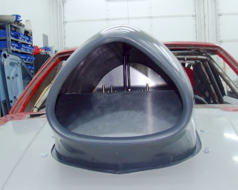 1990 Ford Mustang - A large, grey aftermarket hood scoop is mounted on the hood of a car, with a roll cage visible inside.