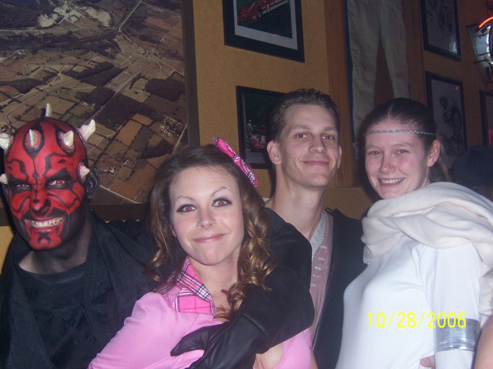 Four people in costumes posing for a photo indoors, with a date stamp of 10/28/2006