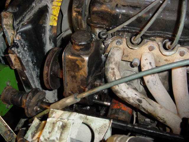 Close-up of engine bay showing power steering pump, hoses, and exhaust manifold
