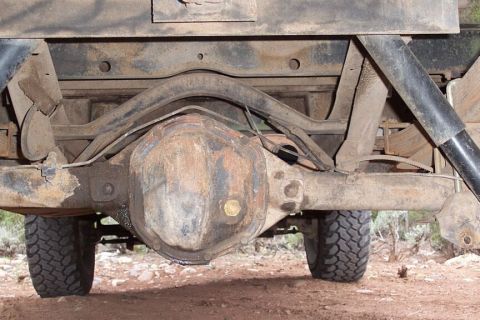 1990 Ford Bronco - The underside of a truck reveals a rusty rear axle and suspension system.