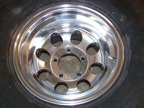1996 Ford Bronco - Close-up of a polished aluminum wheel with eight lug holes, showing the tire tread and a "992" marking on the rim.