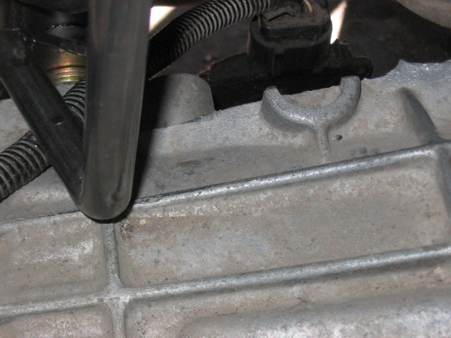 Close-up of a metal engine component with hoses and wiring